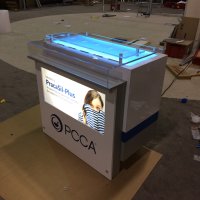 Custom counter designed by Vision Exhibits features a backlit graphic and uplit countertop with interchangeable acrylic risers to display a variety of cosmetic products.